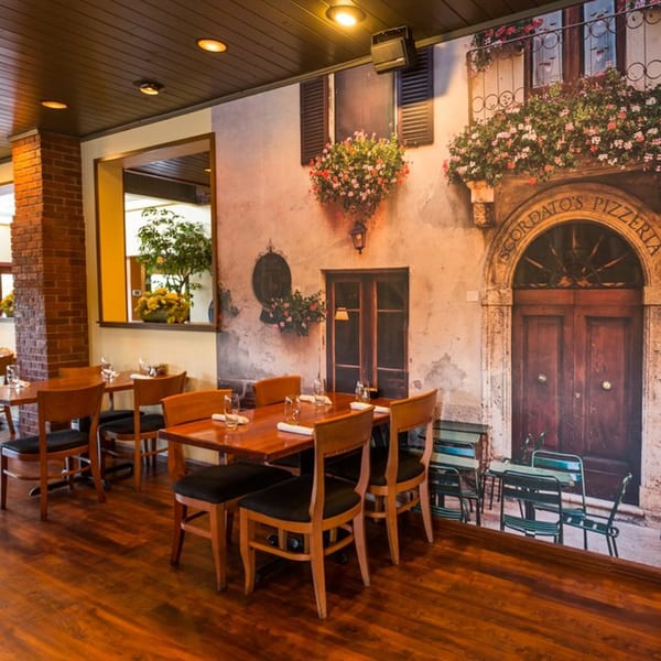 Scordato's Pizzeria dining room with wooden tables and chairs, and a large mural of an Italian street scene.