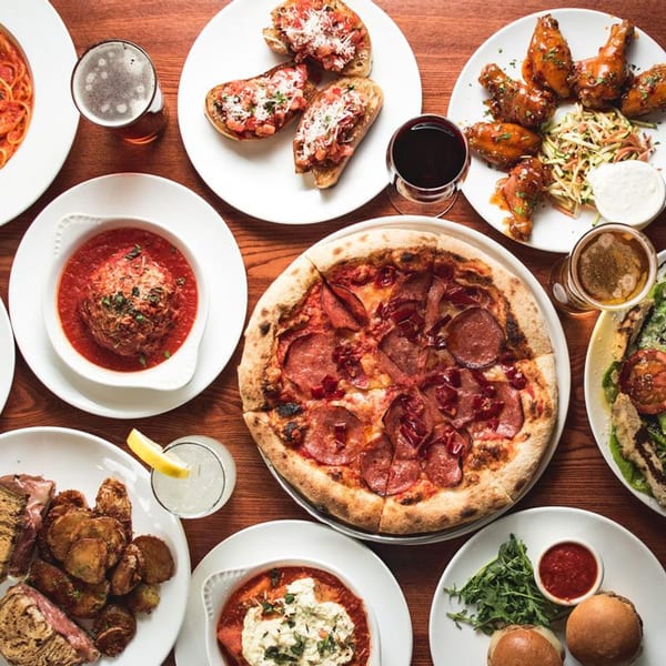 Overhead view of a table laden with Scordato's Pizzeria dishes, including pizza, wings, and pasta.
