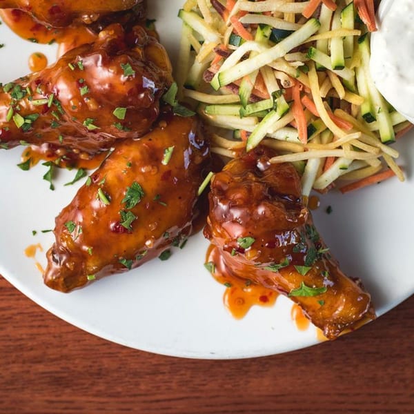 Scordato's Pizzeria's chicken wings coated in a glossy sauce, served with julienned vegetables and dip.